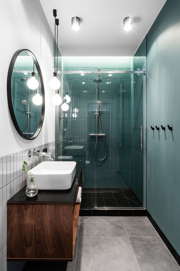 Zöld fal és burkolat a zuhanyfülkében, fekete és szürke padlóburkolatok, fekete mosdópult és kiegészítők