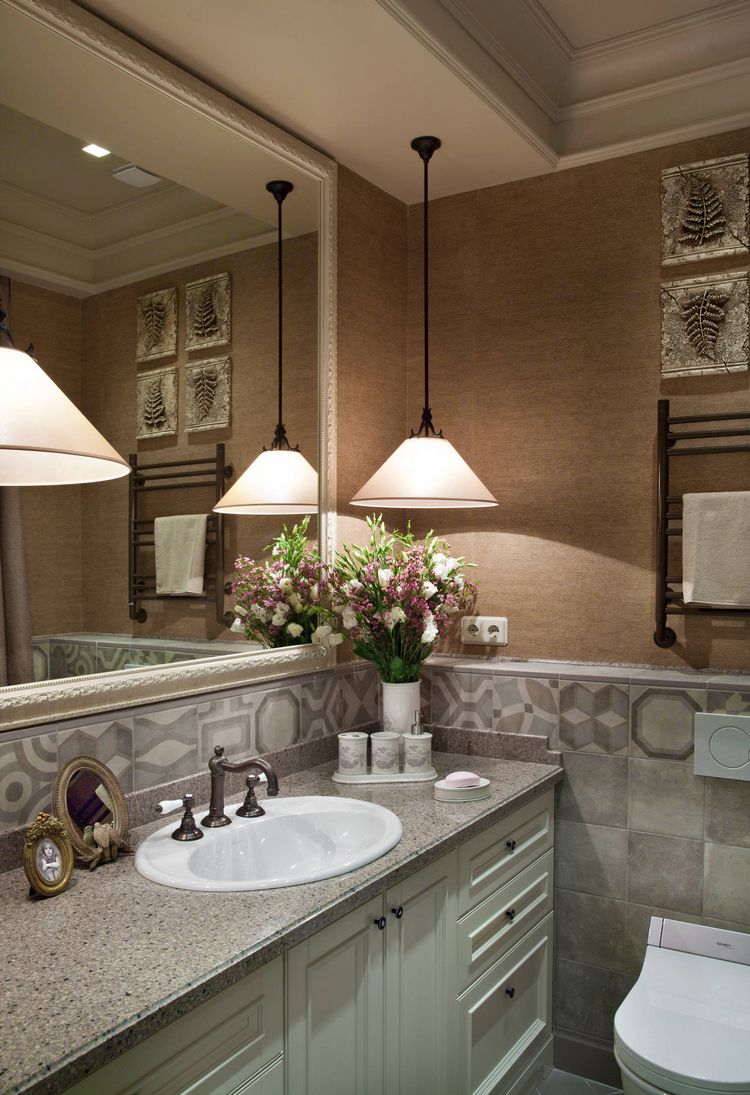 Halványzöld bútor, szürke kő mosdópult, szürke mintás burkolat, nagy tükör és világosbarna tapéta a fal felső részén