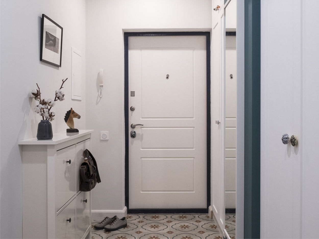 Fehér előszoba, keskeny cipőtartó szekrény, szolid mintás kőporcelán padlólap, fekete ajtókeret