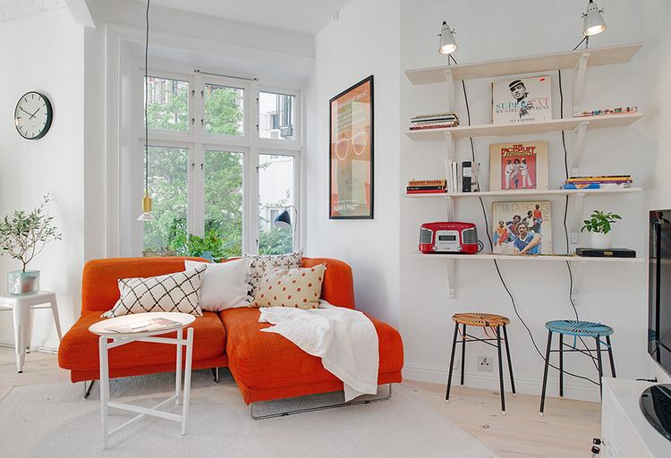 A skandináv lakberendezés egyszerűsége ideális kis lakásokban - ezen a képen egy kis retro hangulat, narancssárga kanapé, fehér falak, nagy ablak függöny nélkül