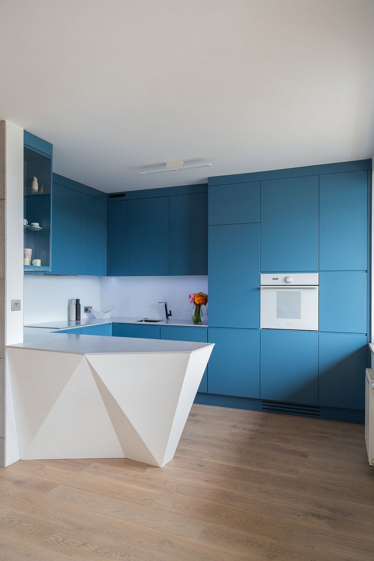 Modern konyha matt kék bútor frontokkal és fehér geometriai formákkal épített pulttal.