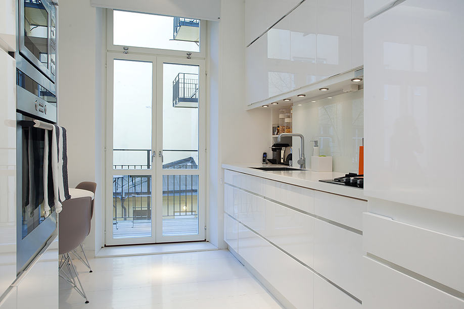 fehér, modern konyha viszonylag tágas közlekedővel és kis erkéllyel - 36nm egyszobás kis lakás