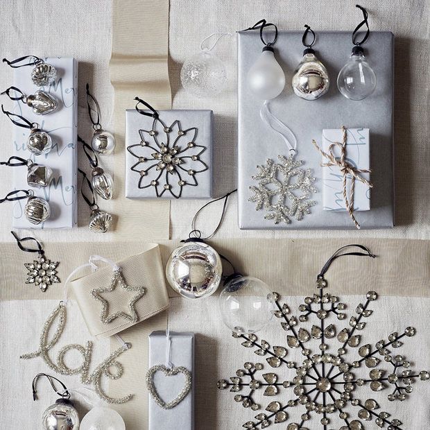 Egy szép ezüst, fehér, bézs papírt nagyszerűen feldobhatunk kisebb karácsonyi díszekkel, papír csillagokkal, szalagokkal, csipkékkel, textíliákkal és apró figurákkal.