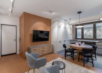 Egybenyitott nappali-konyha tér látványos és funkcionális berendezése fehér és fa felületekkel