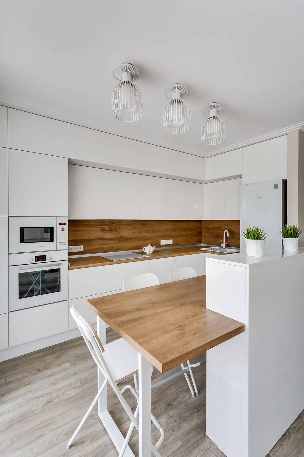 Fa munkalap és hátfal modern fehér konyhában