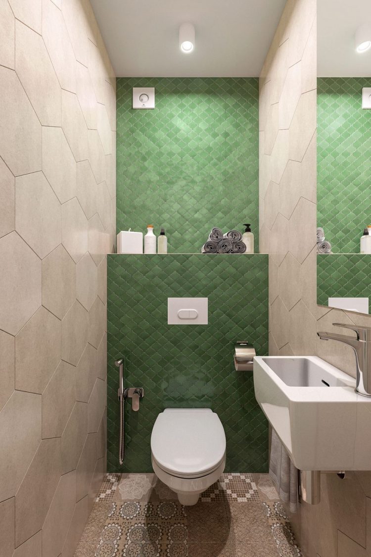 A bézs csempe a falon nagyobb méretű hatszögletű lapokból áll, a WC mögött a fal zöld, kisebb formátumú csempét kapott mutatós formával, a padlóburkolat mintás, a szaniterek fehérek