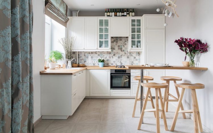 Fehér konyhabútor fa munkalappal és fa étkezőpulttal, bárszékekkel