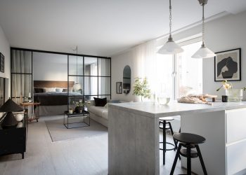 Egy hosszú helyiségben hálószoba, nappali, konyha és gardróbszoba, konyhaszigettel, üvegfallal zónákra tagolva a teret