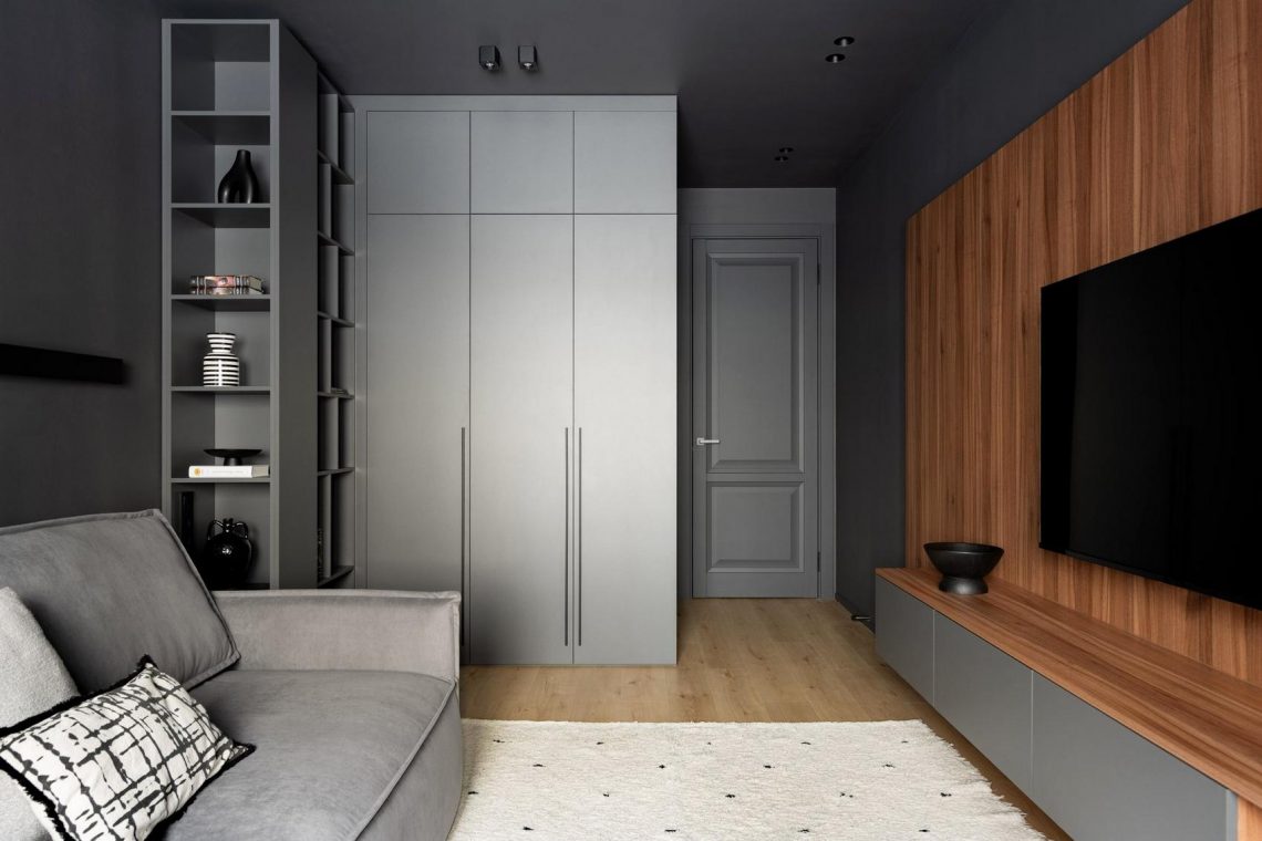 Fiatal férfi otthona szürkébe burkolva, meleg fényekkel és fa textúrákkal