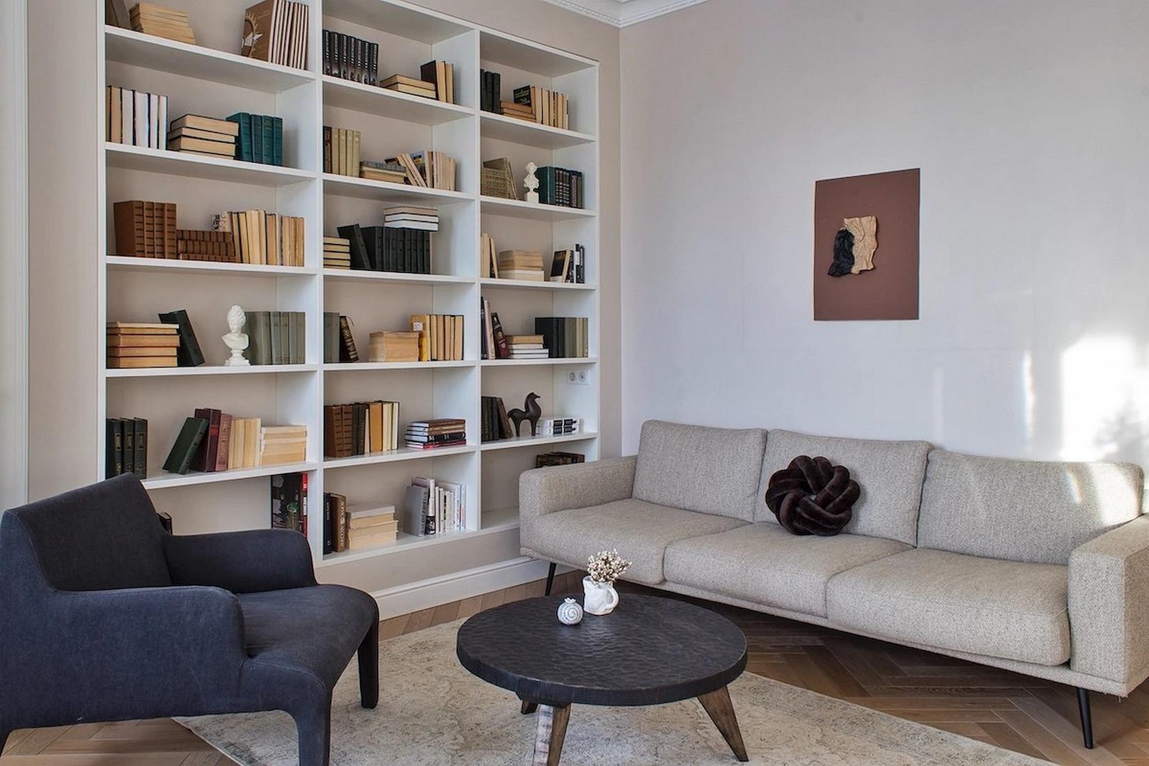 Könyvespolcok egy teljes falon, lágy bézs festés fiatal nő otthonában Könyvespolcok egy teljes falon, lágy bézs festés fiatal nő otthonában