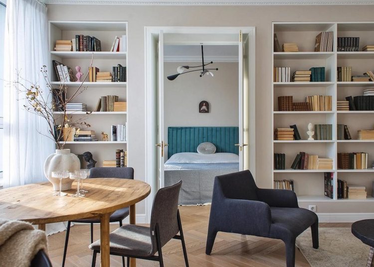 Könyvespolcok egy teljes falon, lágy bézs festés fiatal nő otthonában