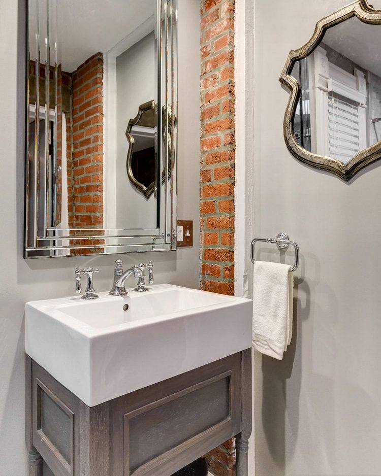 Egy kevés tégla felület mosdó mellett, fürdőszobában, tükrökkel