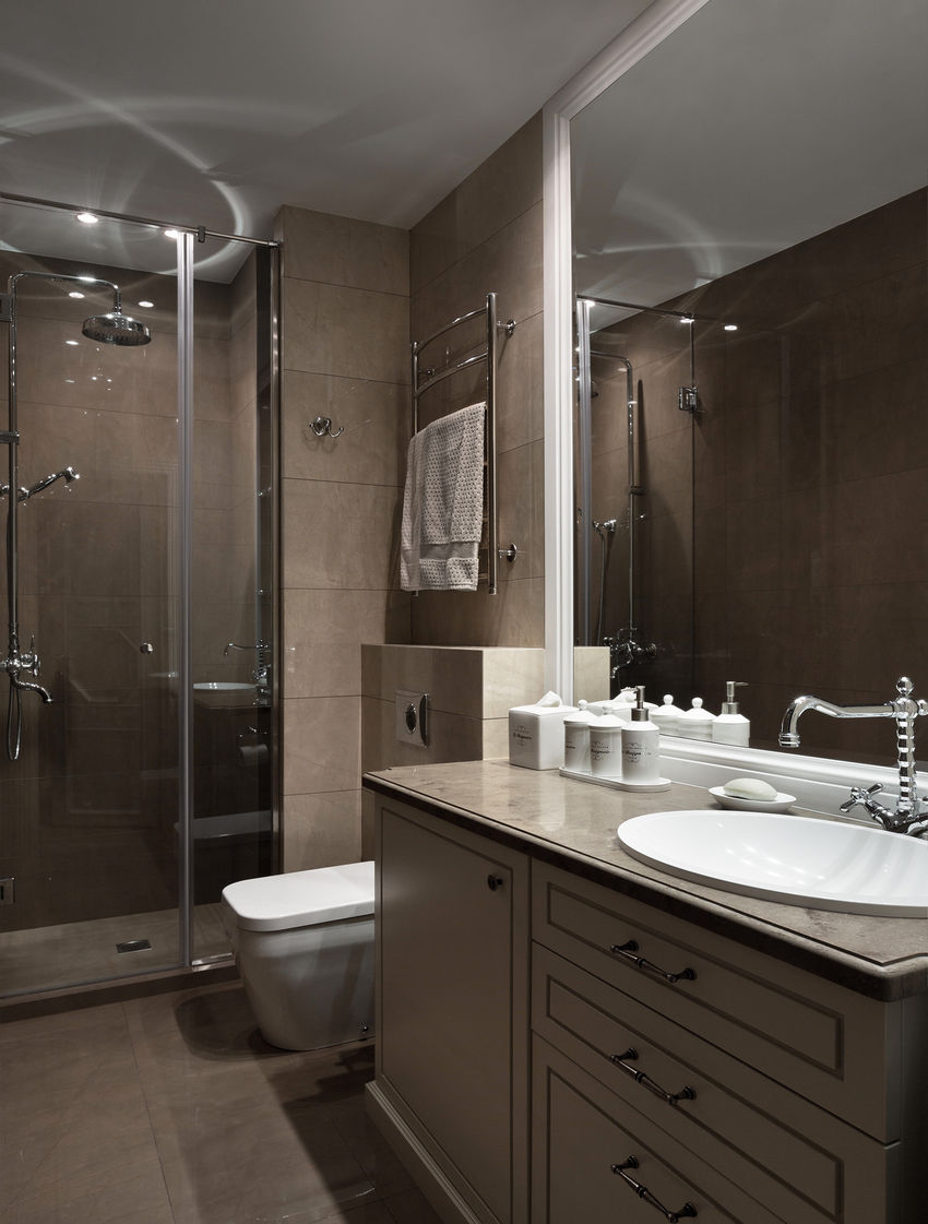 Kellemes, közép- szürkésbarna fal- és padlóburkolatok színben passzoló bútorral és mosdópulttal, zuhanyfülke, nagy tükör