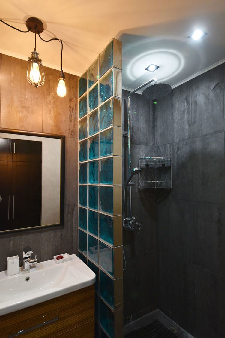 Zuhanyfülke szürke burkolólapokkal, világosbarna falburkolat, kékes árnyalatú üvegtégla válaszfal mosdó és zuhanyfülke között