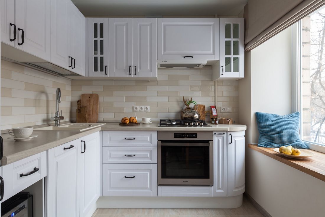 Fehér konyhabútor szürkés munkalappal, fehér-bézs csempe konyha hátfallal