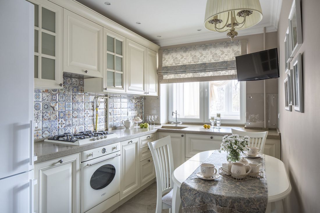 Klasszikus hangulatú konyha fehér bútorral, szürke munkalappal, mintás, színes csempe hátfallal